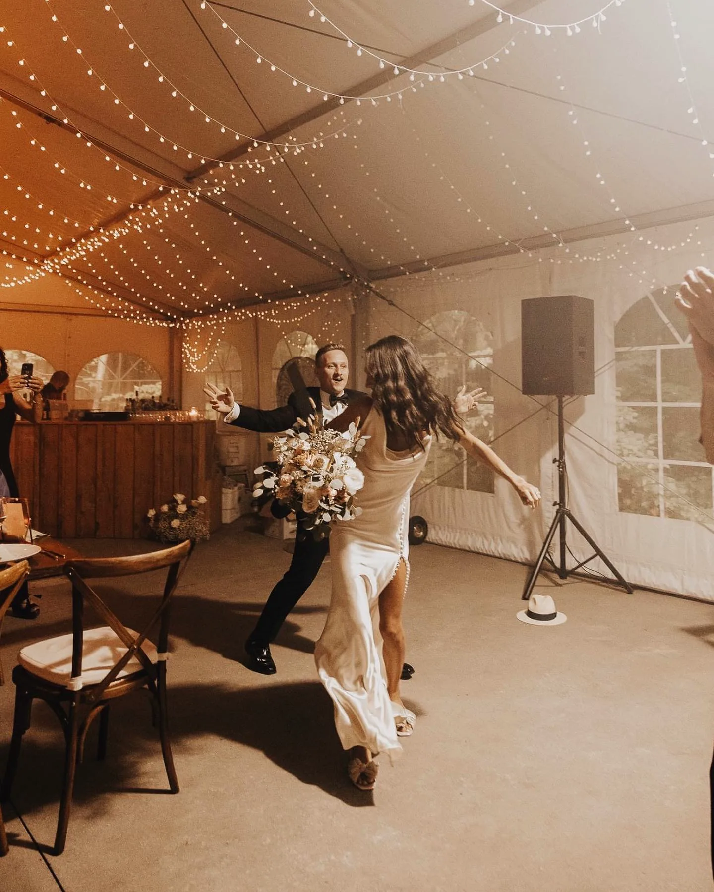 Bride dancing under string lights in a tented venue